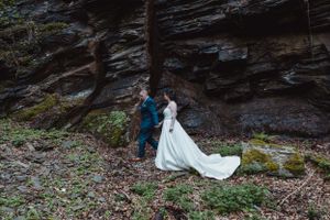 Wedding couple embracing against dramatic rocky cliffs and natural scenery.