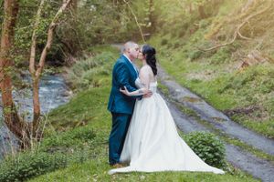 Romantic couple portraits along a winding path with natural greenery and stream.