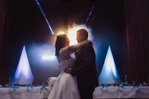 Dramatic first dance silhouettes with blue theatrical lighting at wedding reception.