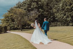 A wedding celebration on manicured grounds with guests walking along a garden path.