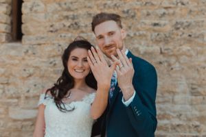 A joyful wedding moment captured against a rustic stone wall background.