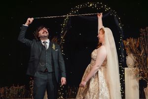 A happy couple shares their first dance at a wedding reception under twinkling lights and rustic decor.