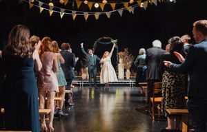 String lights and bunting decorate a wedding reception venue as guests dance and celebrate on the dance floor.