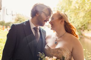 A romantic wedding couple shares an intimate moment in a sunlit garden setting during their celebration.