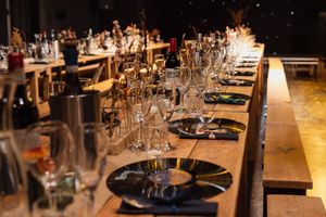 Elegant wedding reception table settings with white linens, glassware and romantic candlelight in a dimly lit venue.