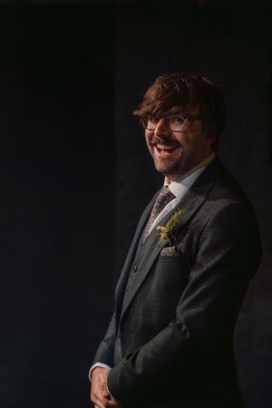 A series of dramatic studio portraits showing a person in a dark suit against a black background.