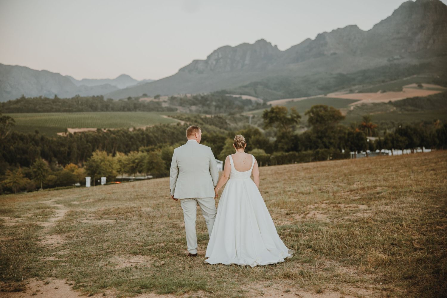 Newlyweds share an intimate moment at sunset on a dirt path in the countryside.