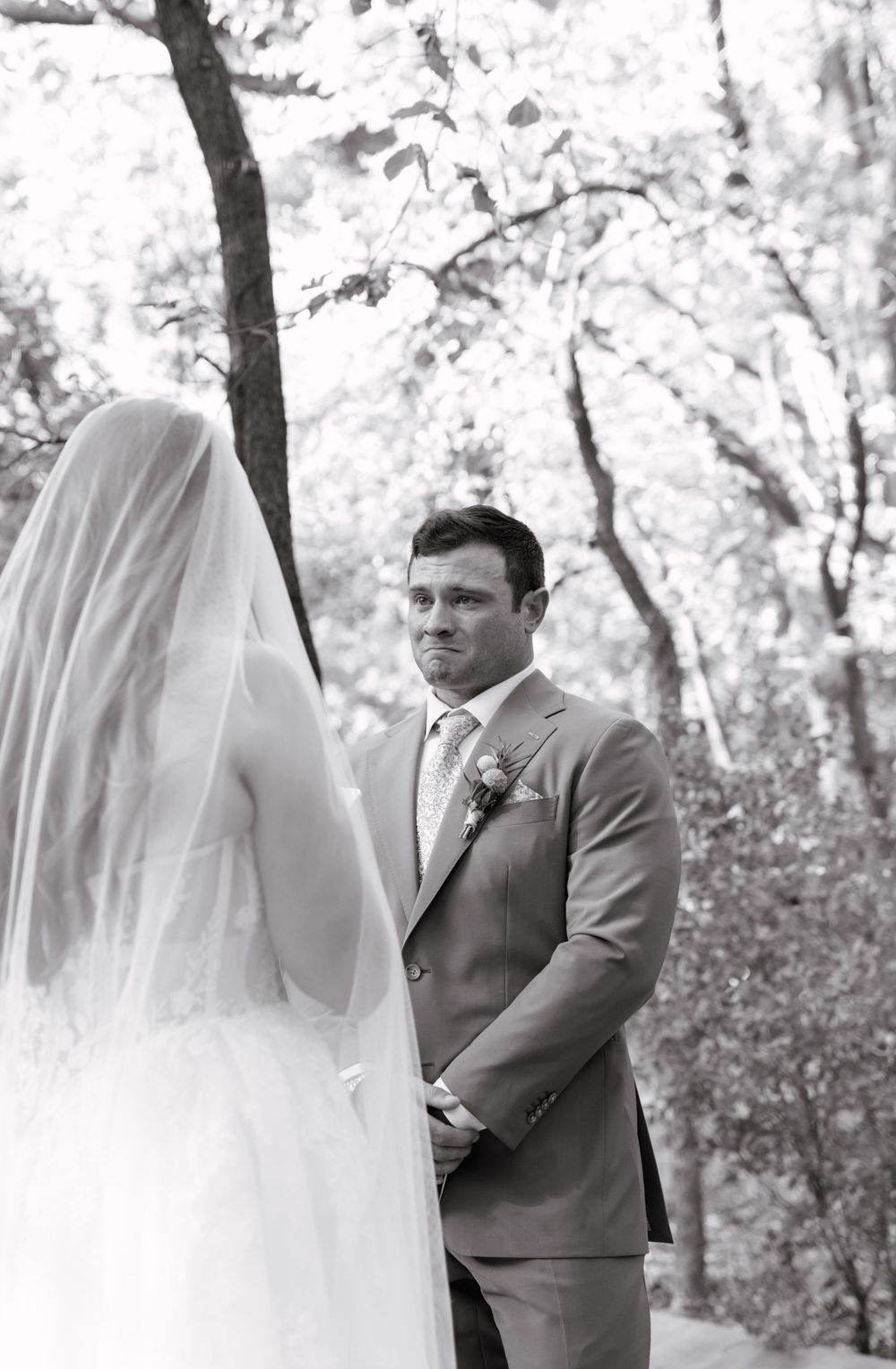Black and white wedding photo series showing a couple's first look moment in a wooded outdoor setting.
