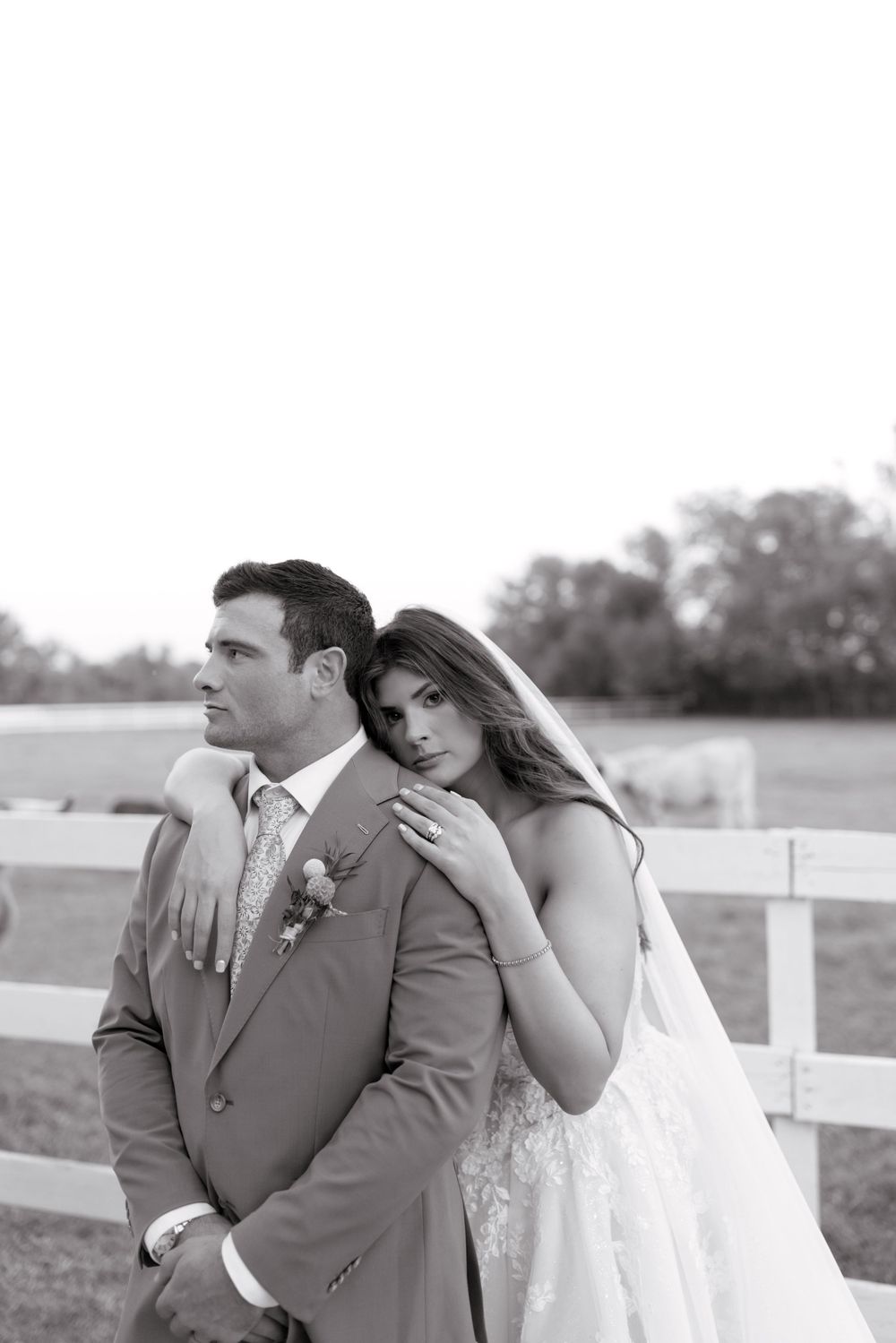 A romantic black and white wedding photo series showing tender moments between newlyweds by a white fence.
