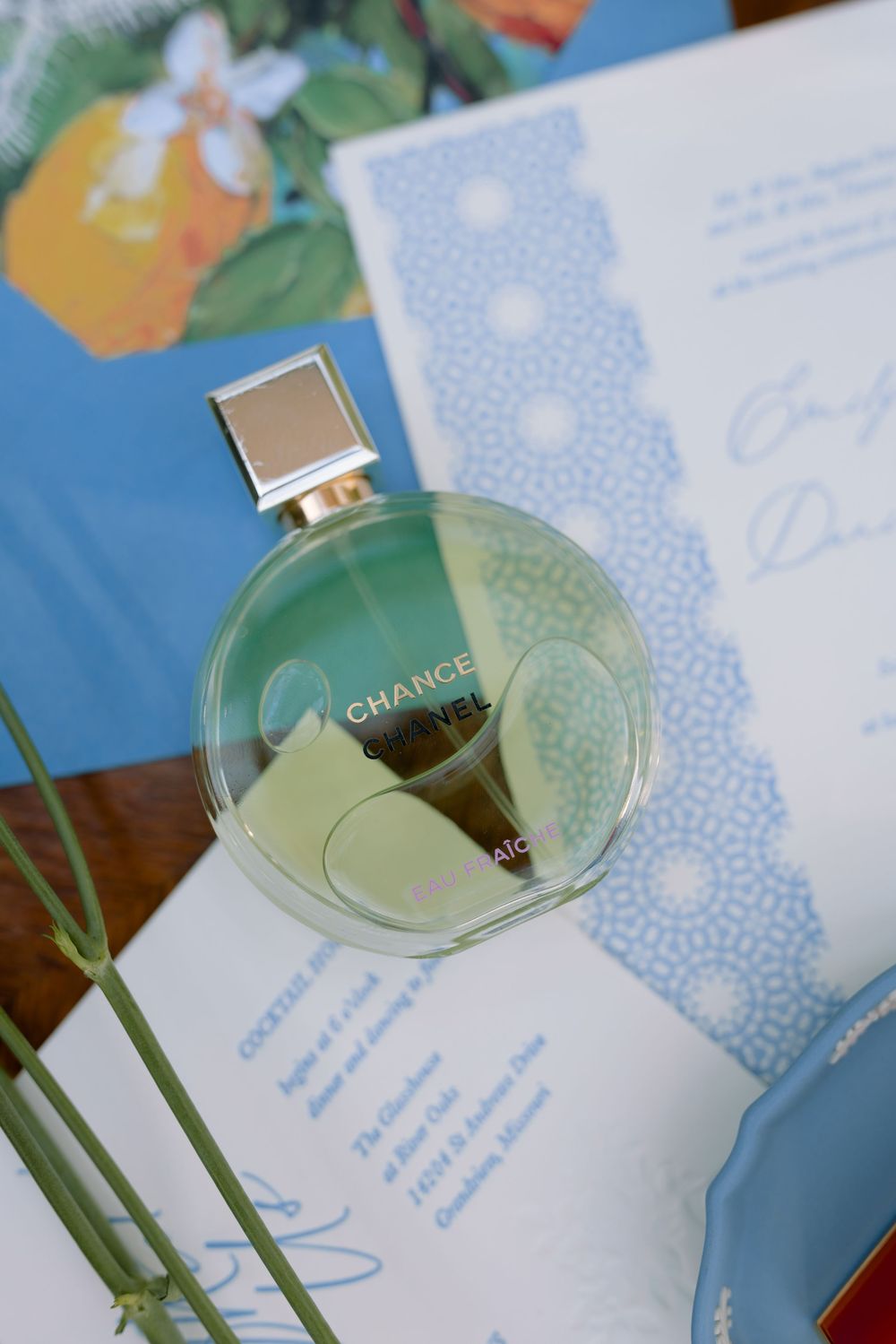 Elegant Chance perfume bottle photographed with floral stationery and delicate blue paper designs in soft lighting.