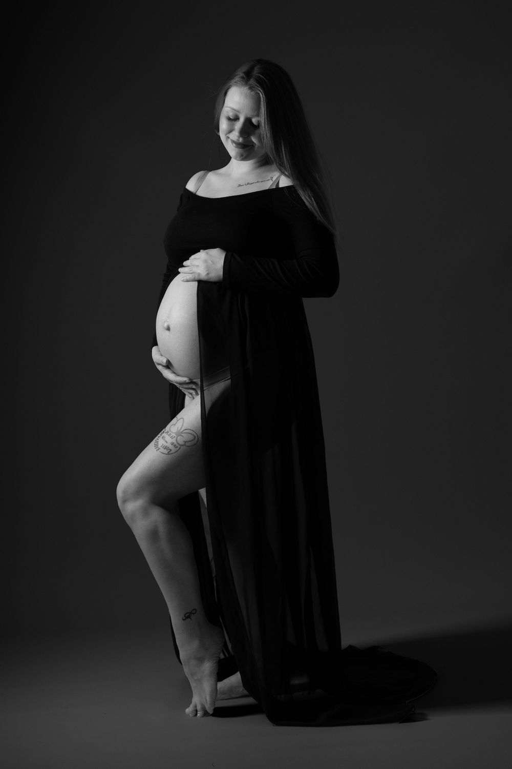 Sort-hvid graviditetsportræt i studie med elegant kjole og blød belysning – fotograferet af lokal fotograf i Jægerspris, Frederikssund og No