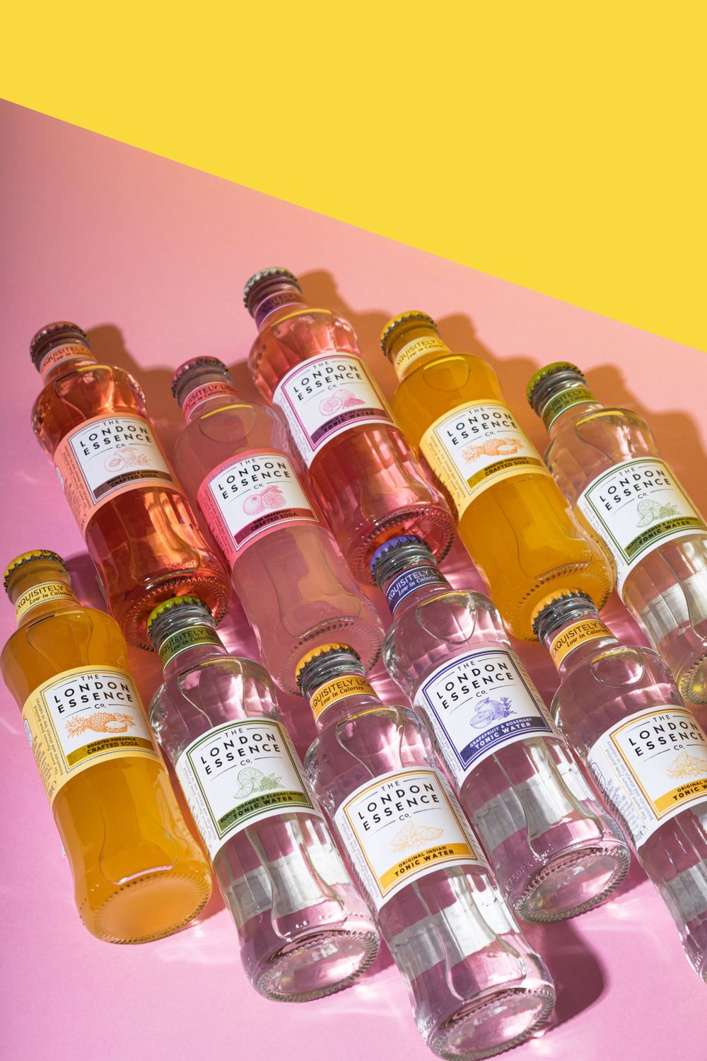 Collection of French Tonic bottles arranged on pink and yellow diagonal background.