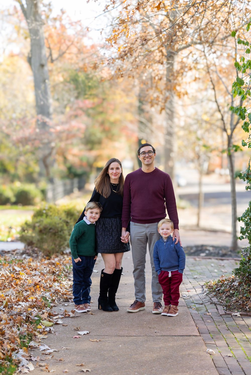A group poses together on a brick pathway surrounded by fall foliage.