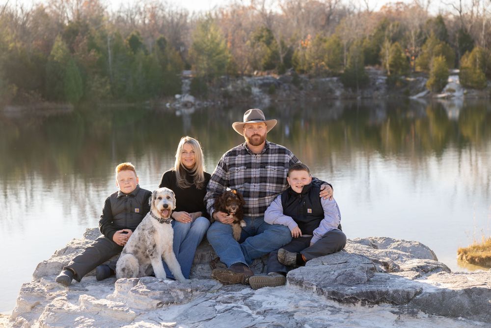 A group sits together with their dogs on rocky outcrop by a serene lake during autumn.
