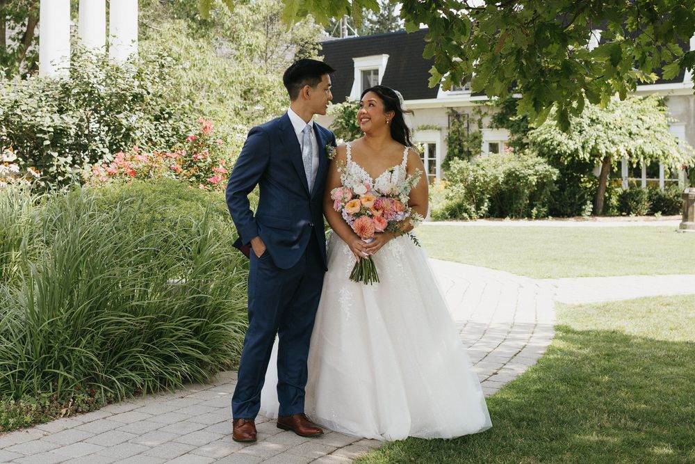 A couple shares a romantic moment in a lush garden setting during their wedding celebration at Langdon Hall in Cambridge Ontario