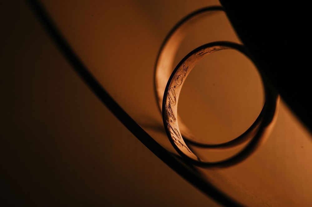 Close-up macro shot of a glass ring casting warm amber shadows on a curved surface. Fotógrafo de bodas en Formosa
