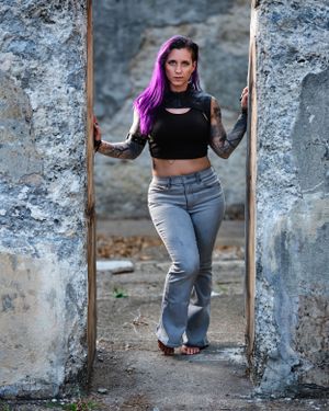 David G Holt Photography - Urban portrait of model with purple hair posing between concrete walls in casual attire.