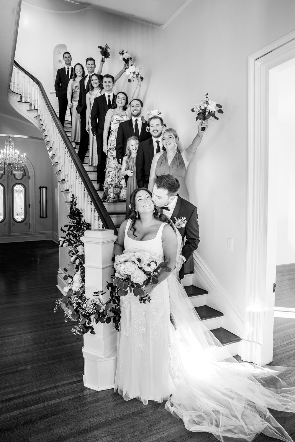 A sequence of black and white wedding photos showing a bride ascending a staircase with guests watching from above.
