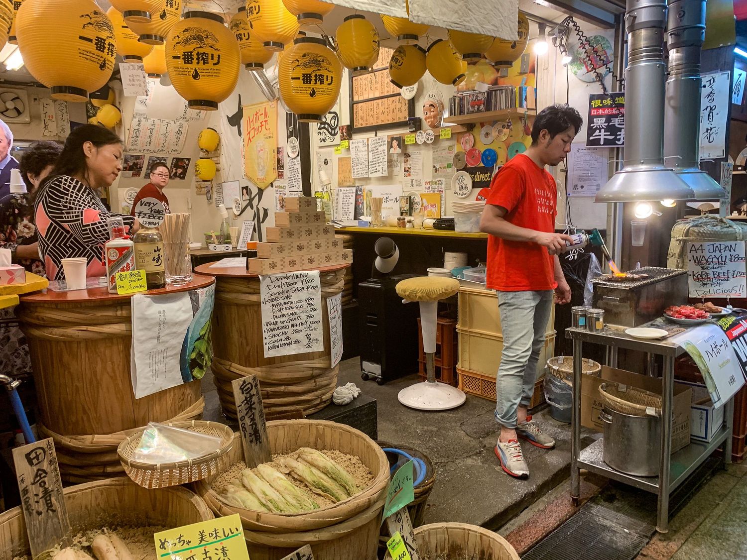 Interior shot of a traditional Japanese yakitori restaurant with lanterns, kitchen counter and diners at the bar.