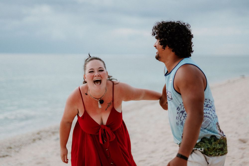 A candid moment of joy captured between two people on a beach.