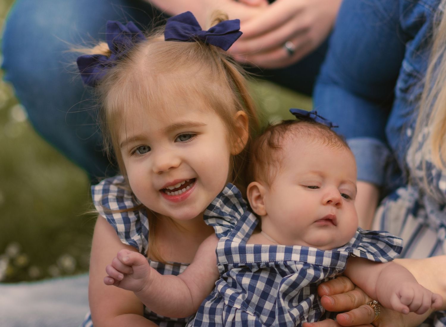 Big sister holding little sister and smiling at camera.