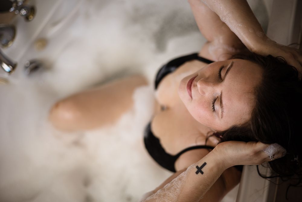 Artistic boudoir photography with soft lighting in a bathtub setting.