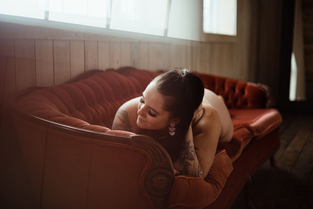 Moody boudoir photography with dramatic window lighting.