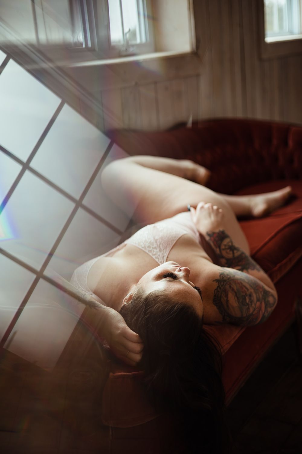 Intimate portrait with natural window light creating geometric patterns.