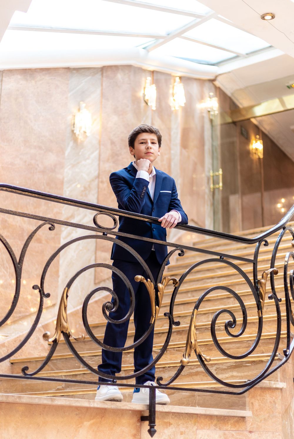 Navy suit outfit styled on ornate marble staircase with decorative railing.