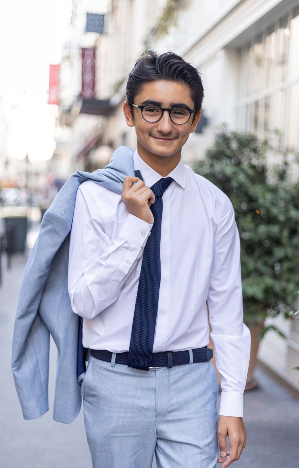 A professional in a business suit and tie smiling on a city street.