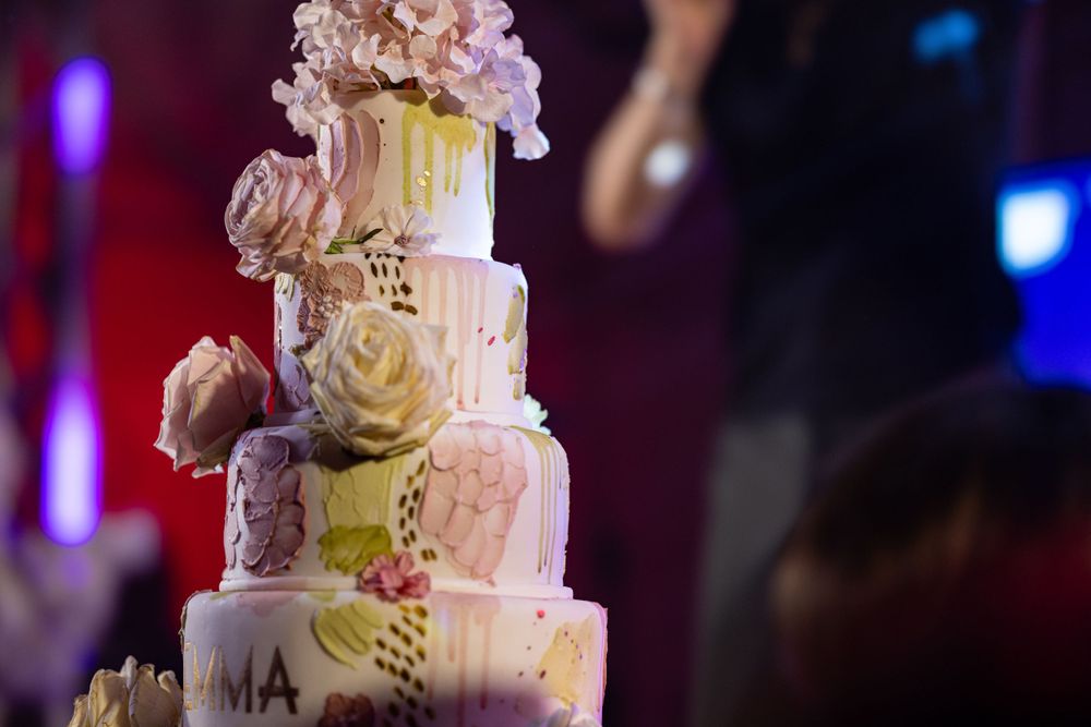 Elegant white wedding cake decorated with pink roses and gold accents.
