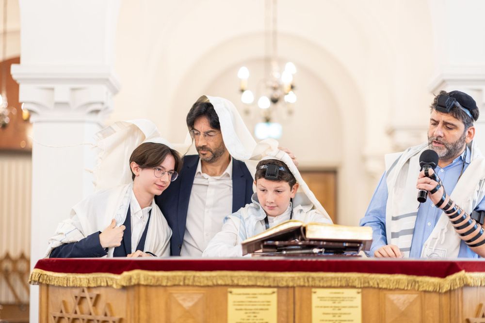 Group gathered around Torah scroll at synagogue bimah during religious service.bar mitsva