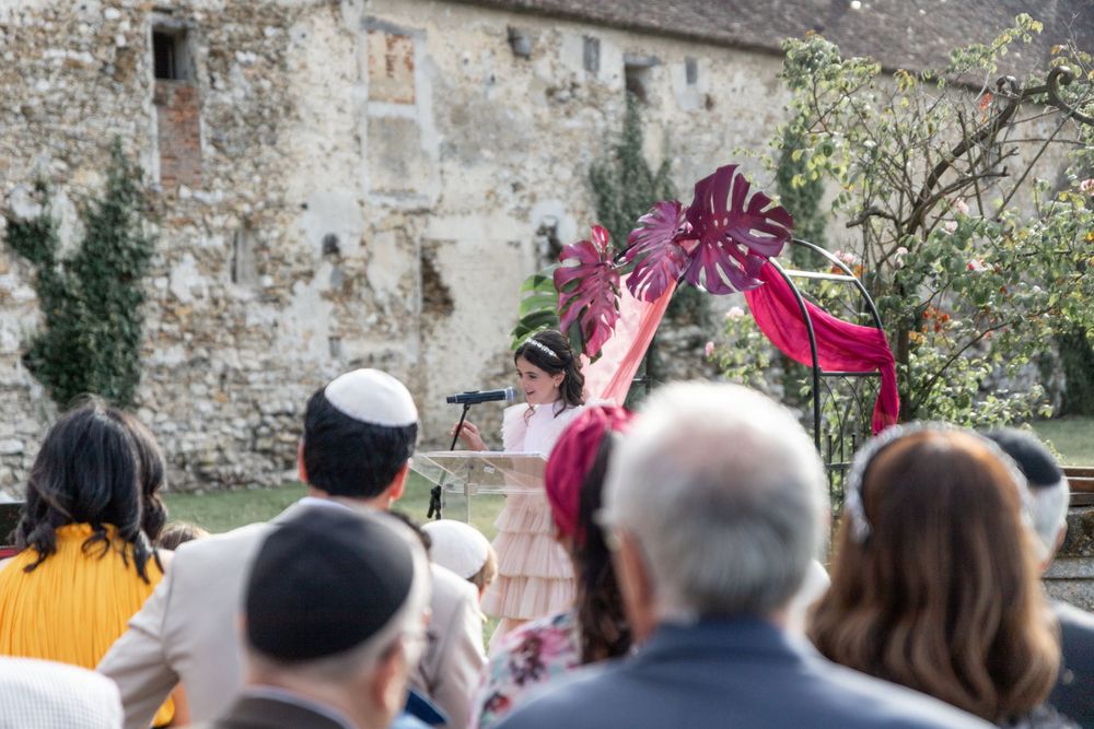 Outdoor Jewish celebration with crowd watching ceremony against stone building backdrop.bat mitsva