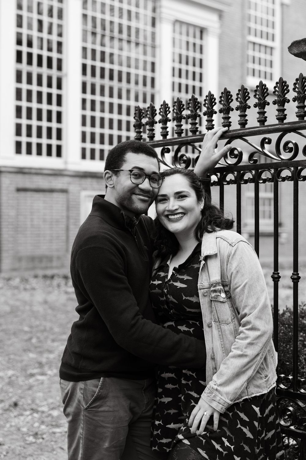 A couple shares a romantic moment by an ornate iron fence.