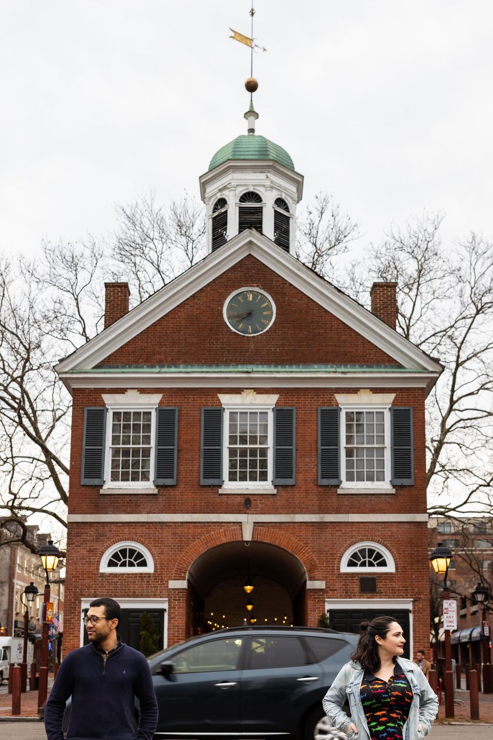 Colonial brick building with green dome cupola and clock tower in historic setting.