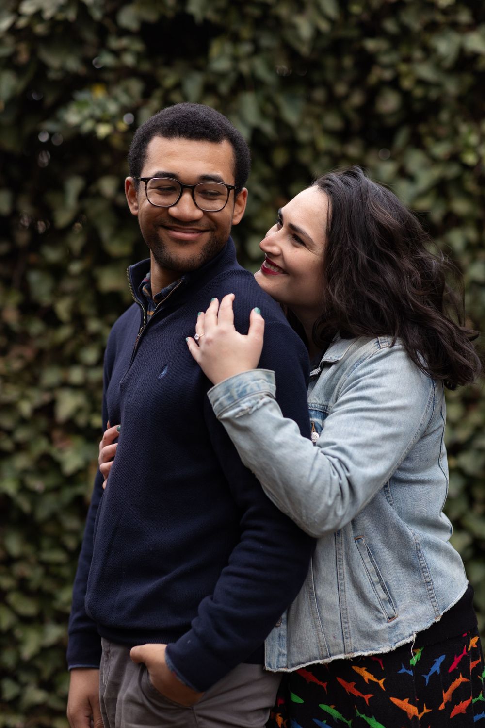 A couple shares a joyful embrace against green foliage background.