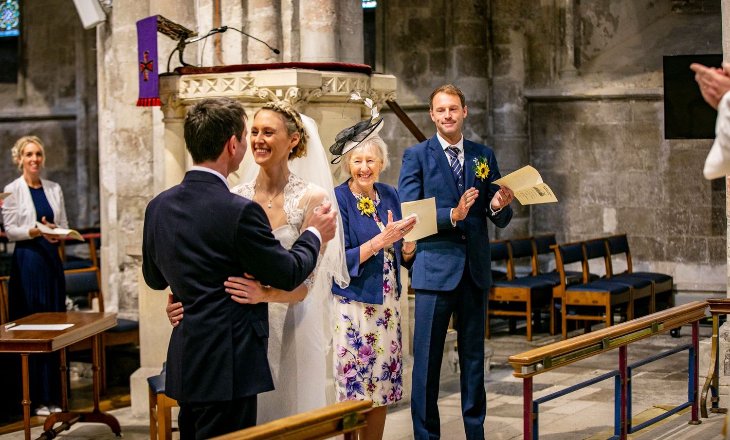 Guests gather in the aisle of a grand cathedral during a wedding ceremony.