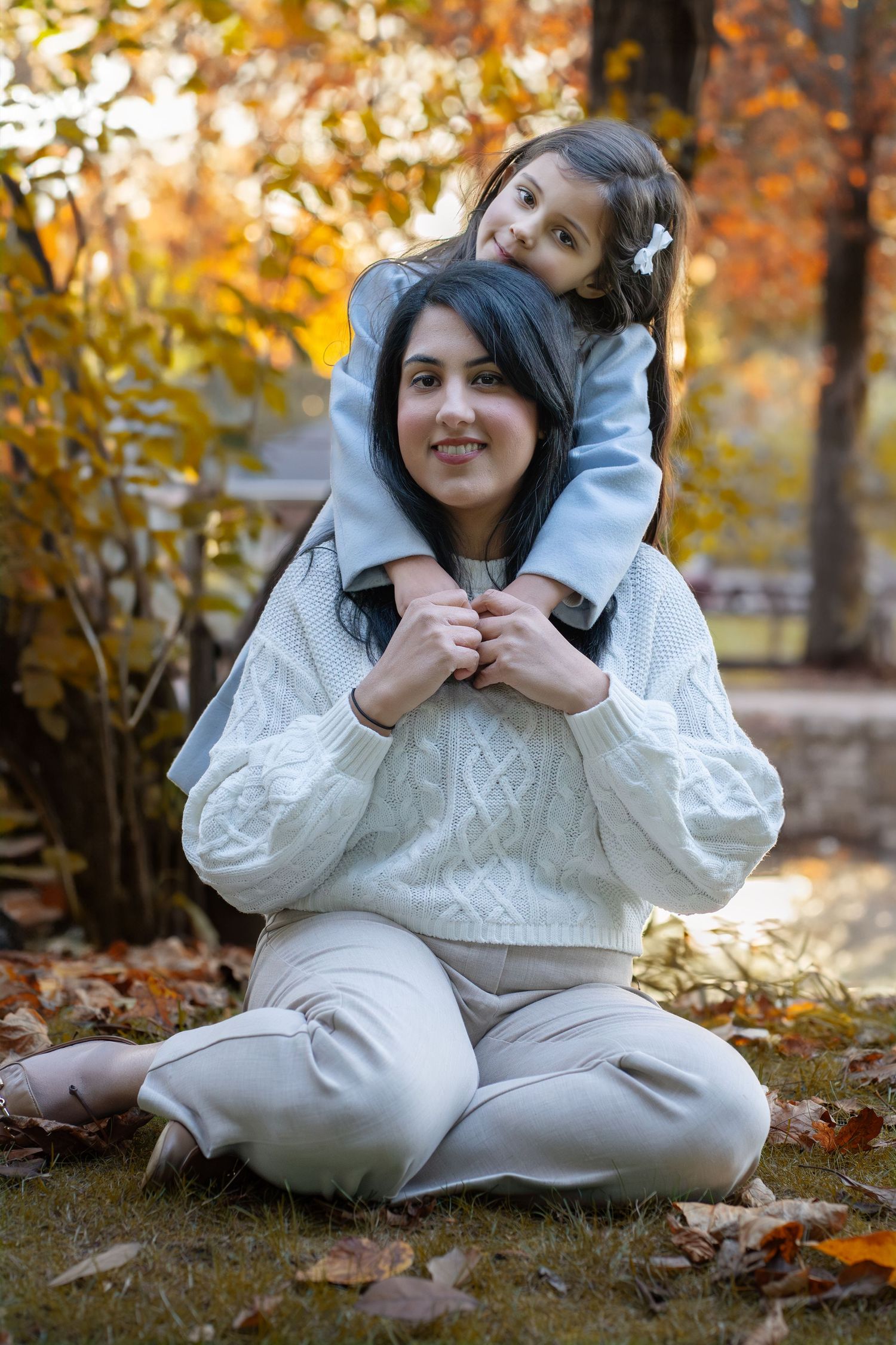 A heartwarming autumn portrait showing a playful moment between two people in white sweaters among fall foliage.