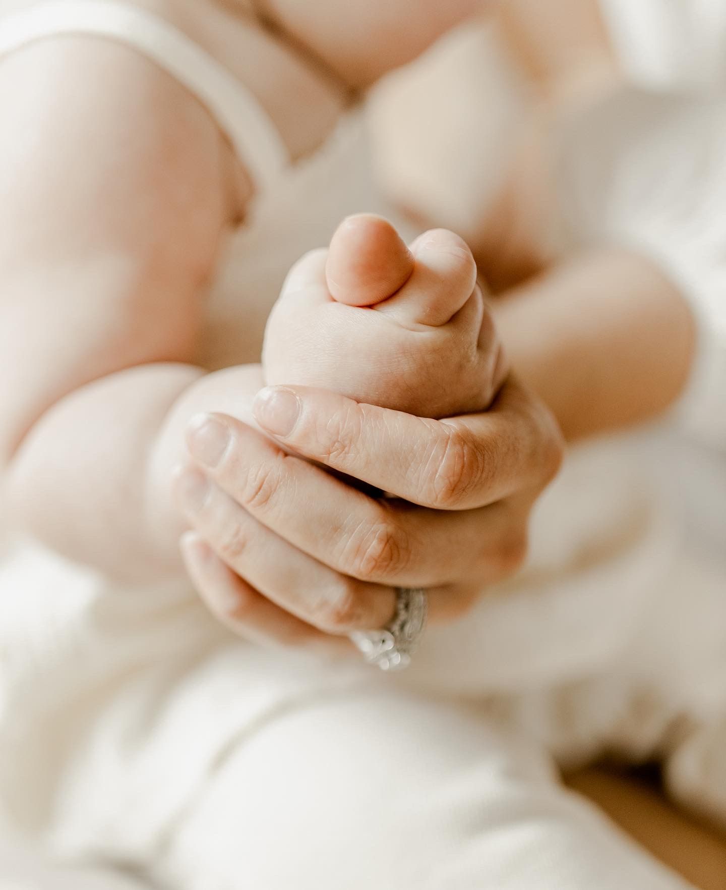 Close-up shot of gentle hands cradling tiny baby feet in soft natural light.