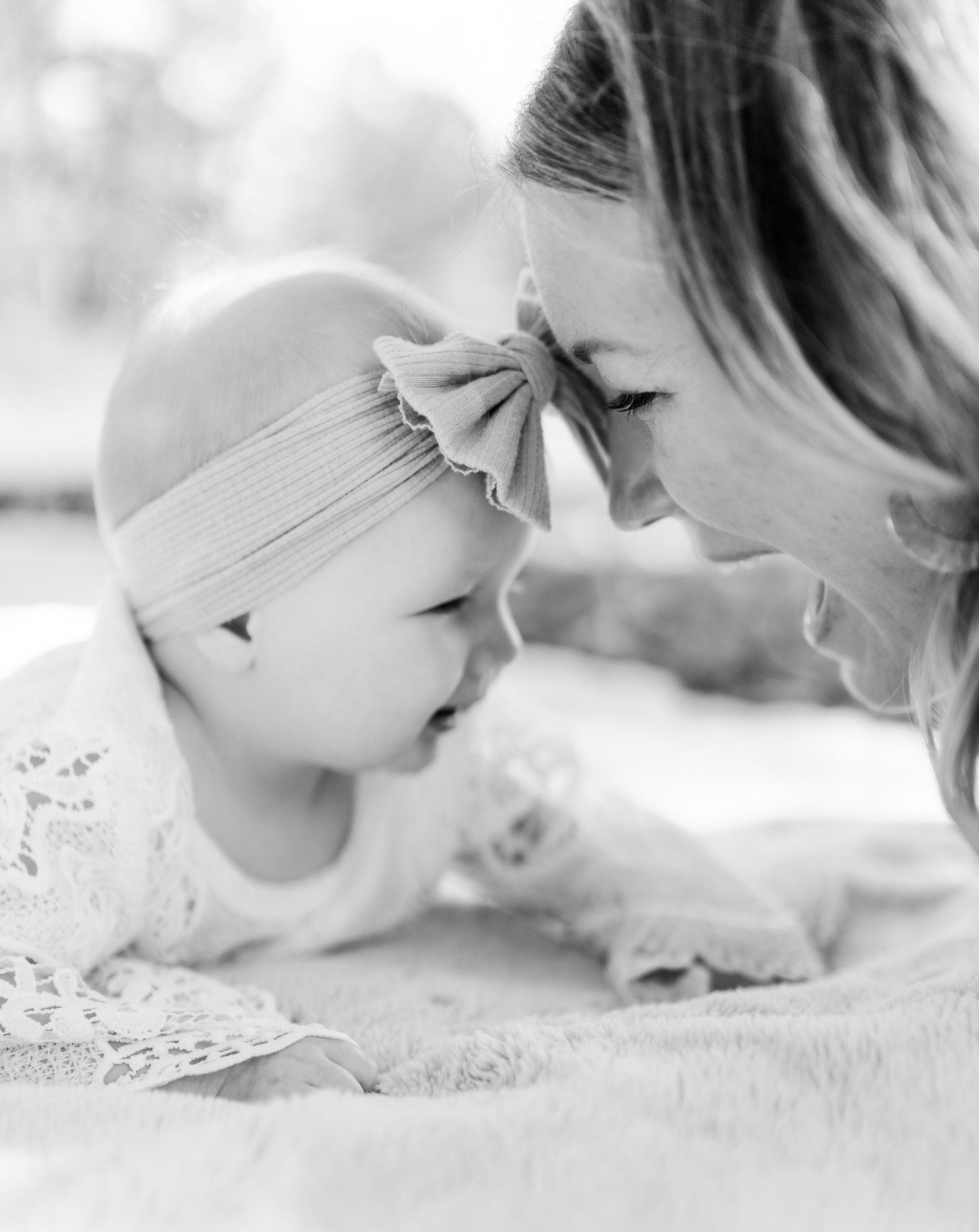 Tender moment between mother and baby touching foreheads in black and white.