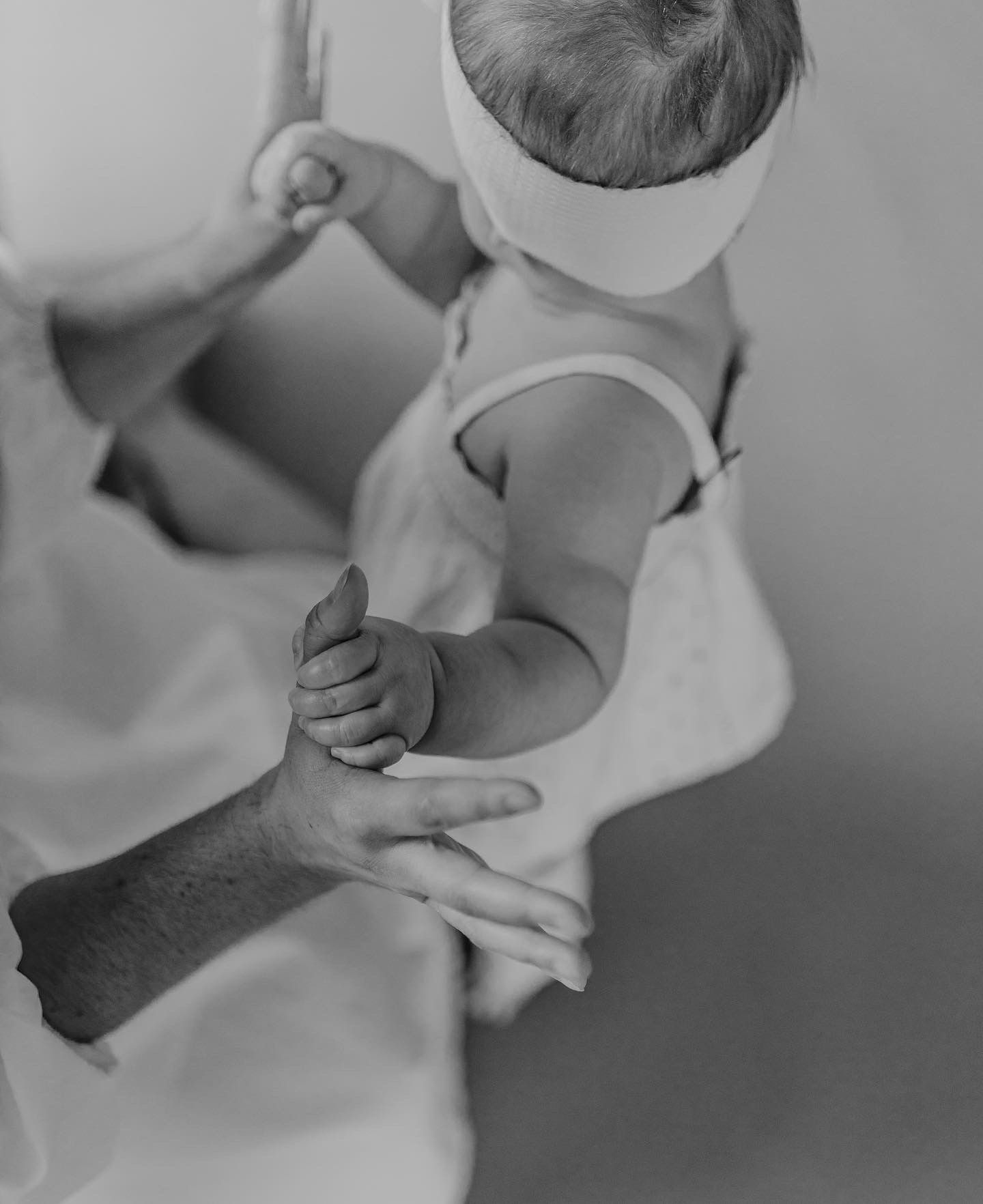 A tender black and white close-up of hands holding and supporting a small baby.