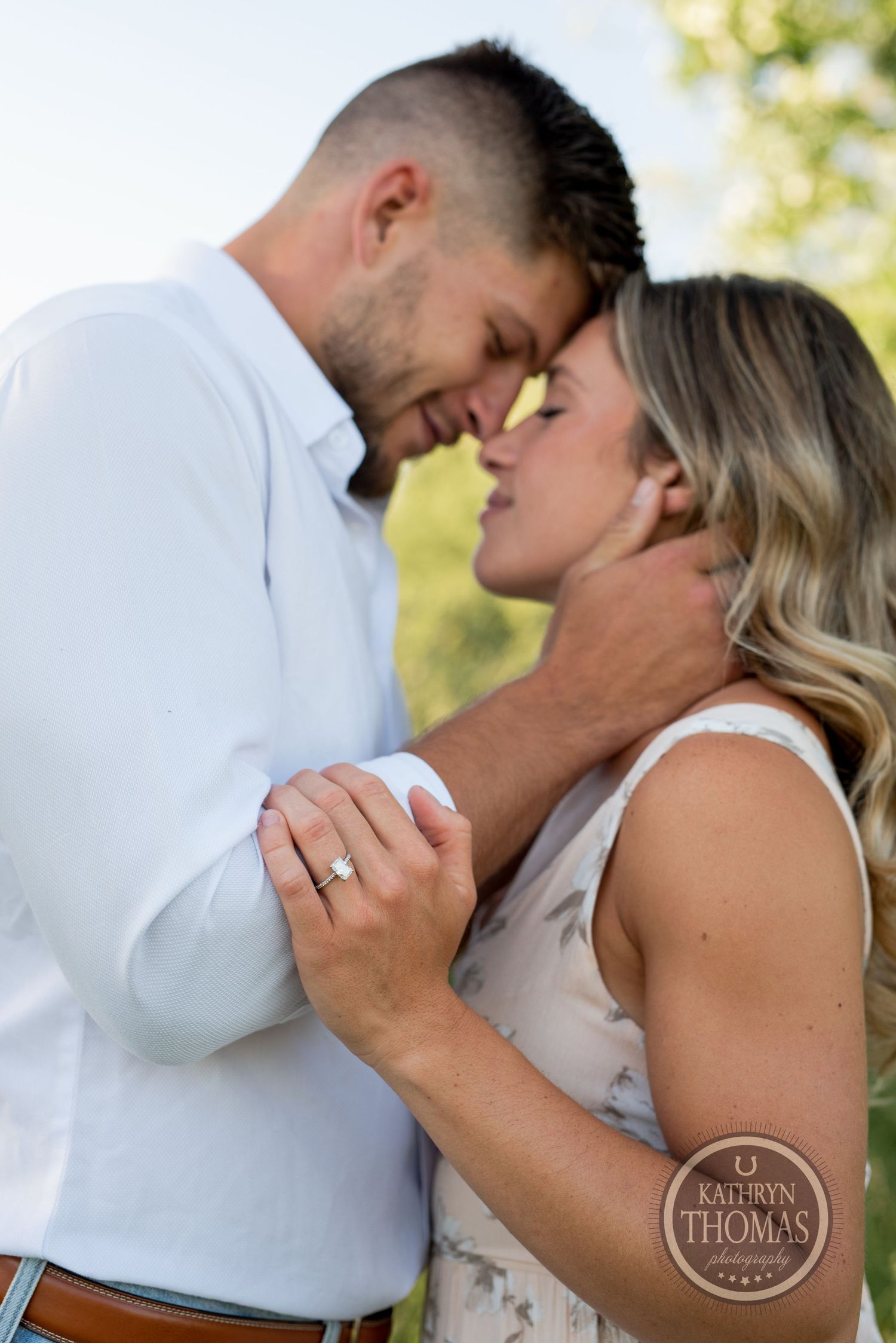 A close-up of a couple sharing an intimate moment while showing off an engagement ring.