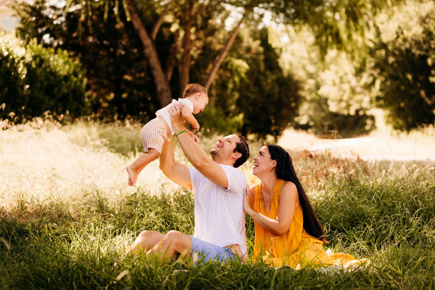 Father holds up one year old boy while mother looks on