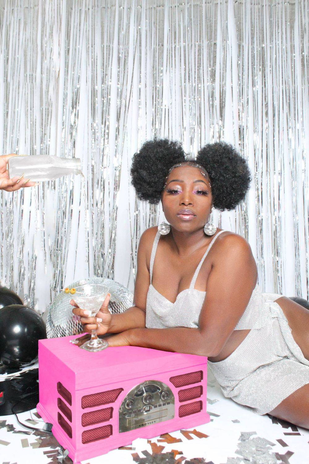 Party scene with silver tinsel backdrop featuring retro pink radio and disco ball decorations.
