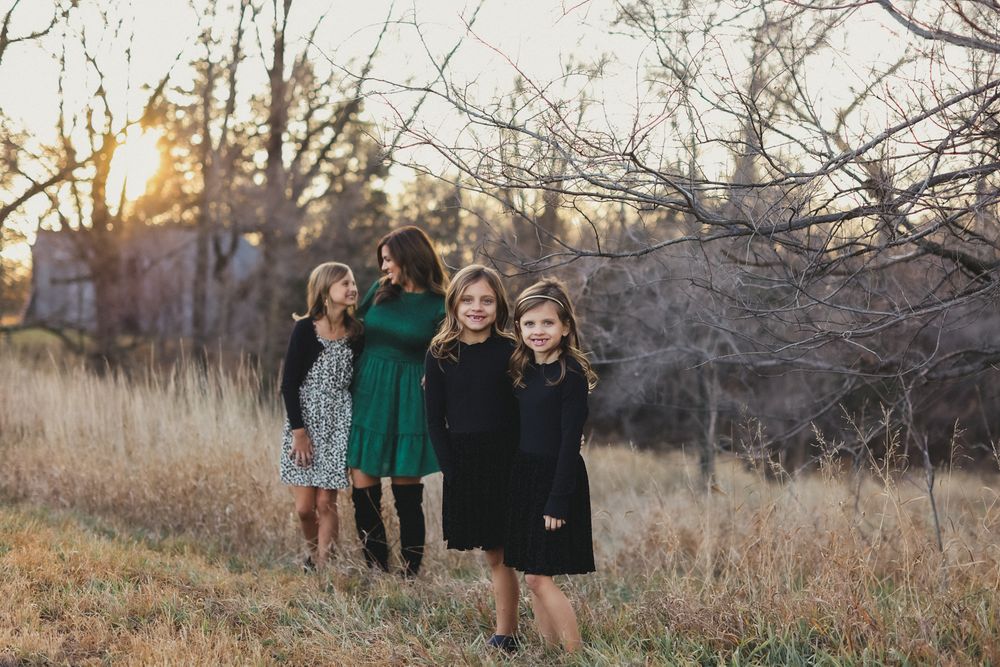 Group photo in field wearing coordinated dresses during sunset.
