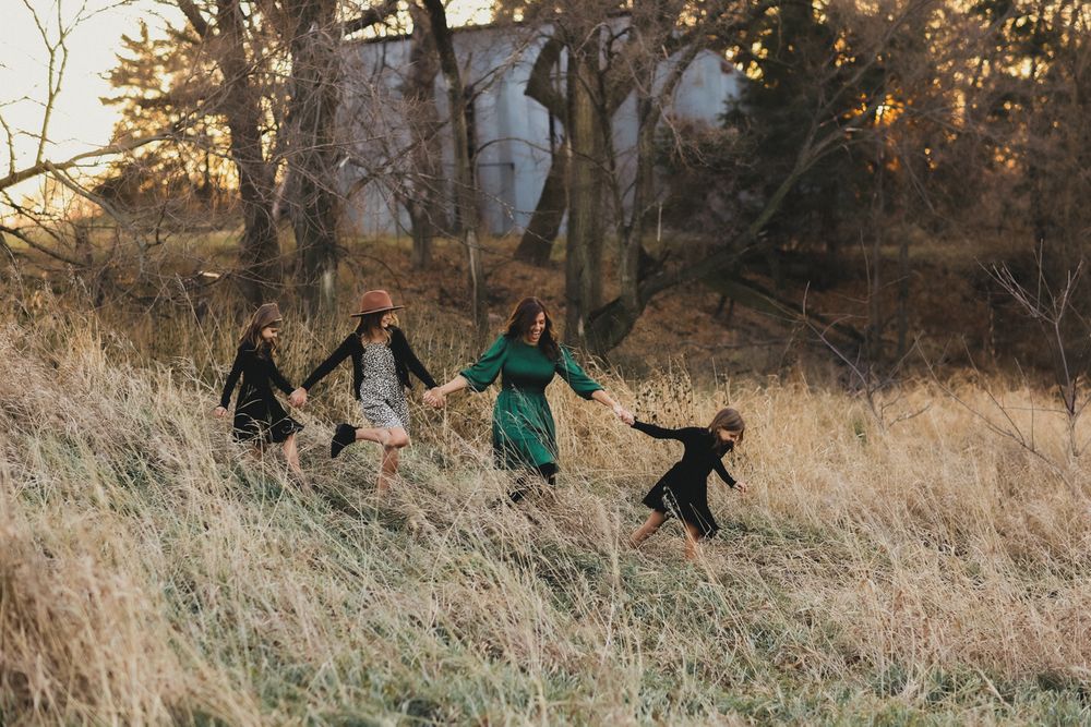 Family enjoying playful moments together in a golden field during sunset.
