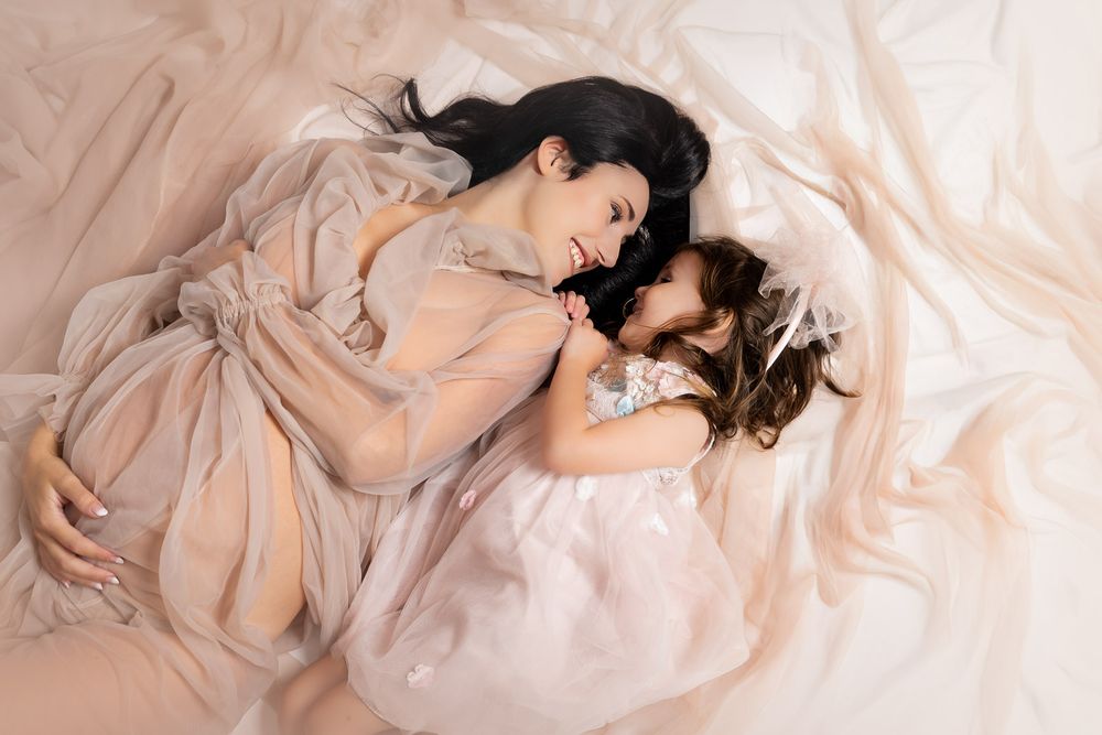 A person lies gracefully on cream-colored fabric in an artistic boudoir photography composition.