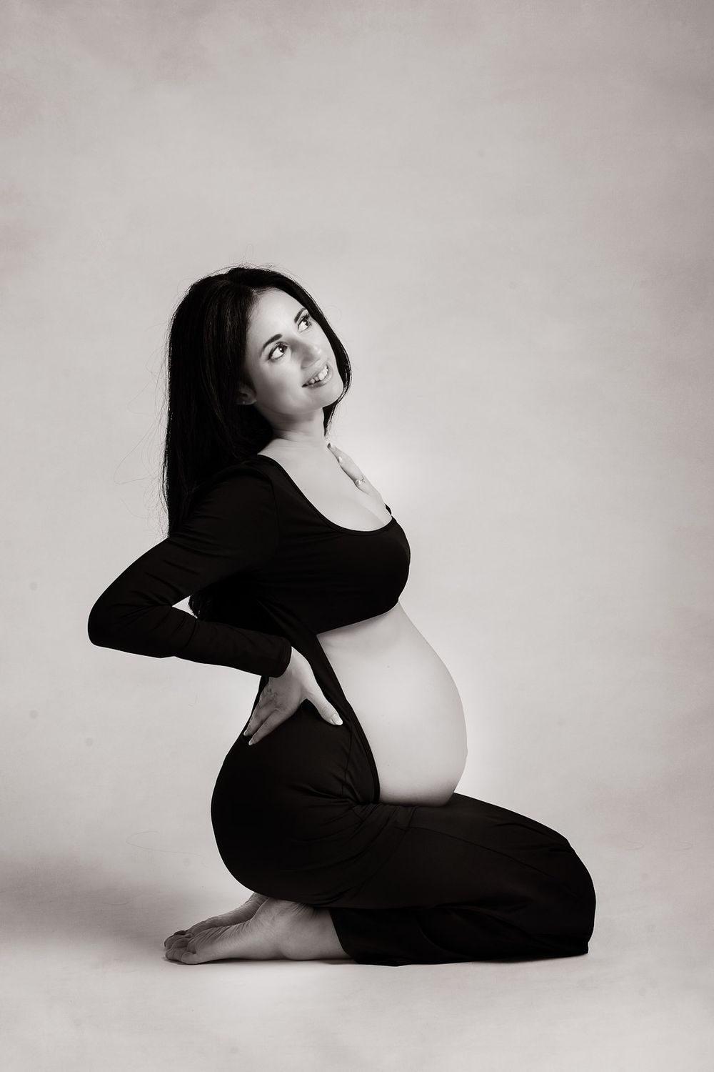 Black and white artistic maternity photo series showing graceful poses against a light background in minimalist style.