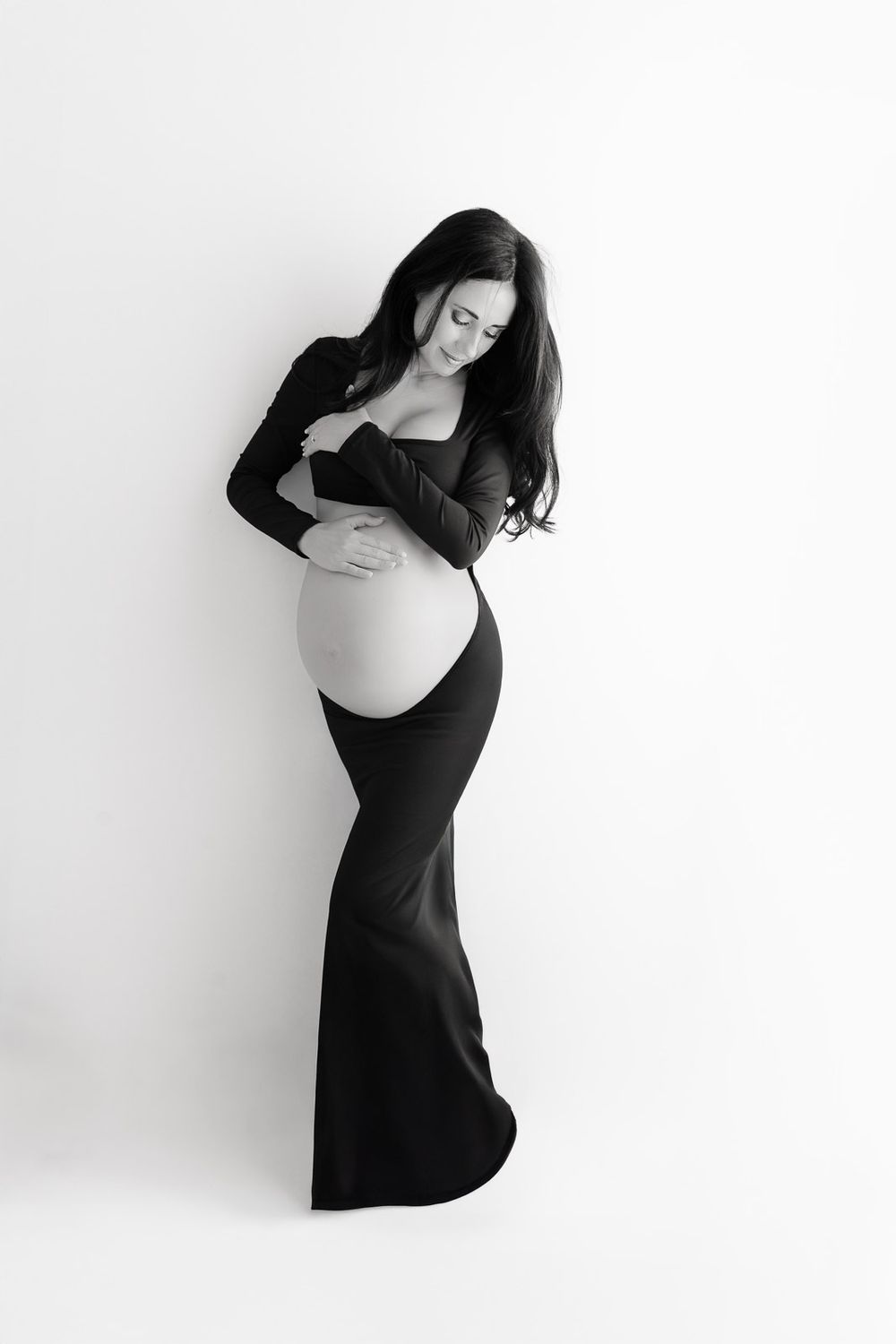 A series of black and white artistic maternity photos showing a woman in a black dress cradling her pregnant belly.