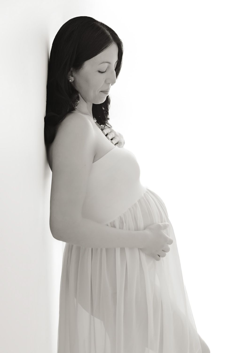 A series of artistic maternity photos showing a pregnant woman in white flowing fabric against a light background.
